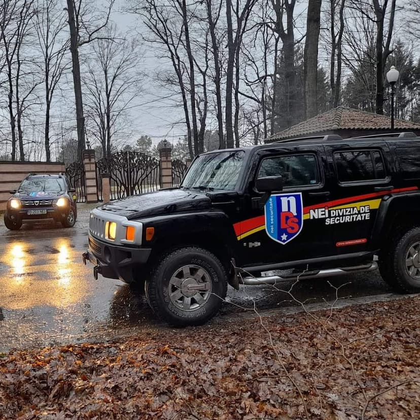 Hummer și Dacia Duster cu însemnele NEI la intrarea unei proprietăți