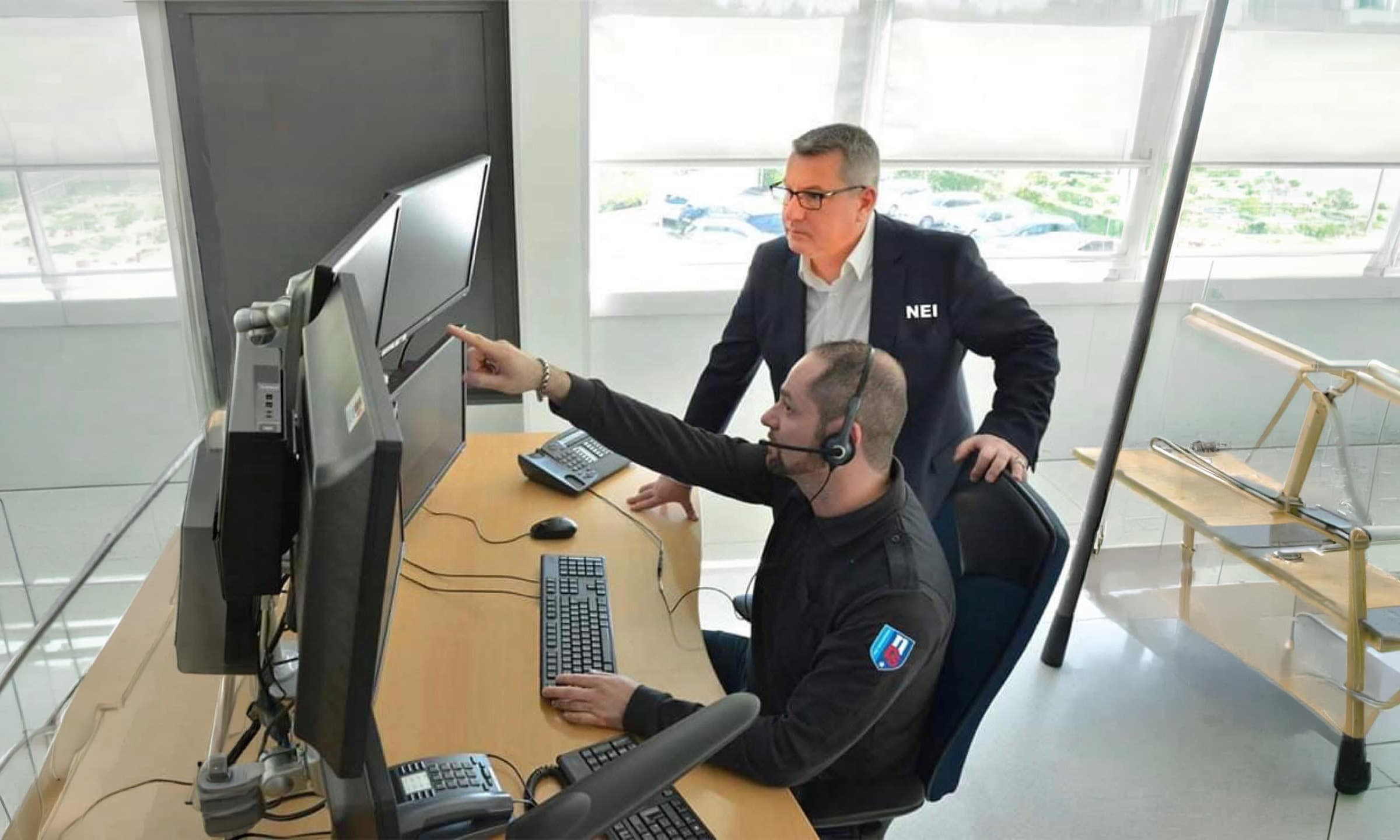 Dispeceratul NEI: un operator cu cască arată spre monitoare, lângă un coleg