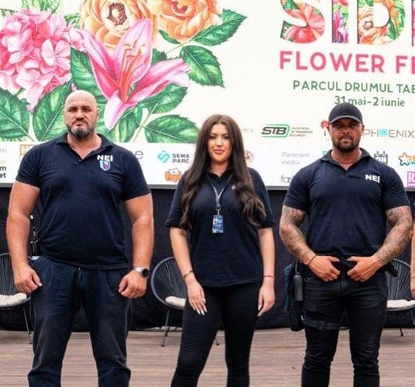 Trei membri ai echipei NEI, în tricouri cu sigla companiei, la un festival