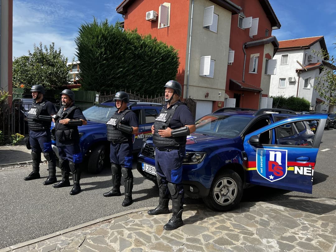 Echipaj NEI în echipament de protecție, lângă autovehiculele de intervenție