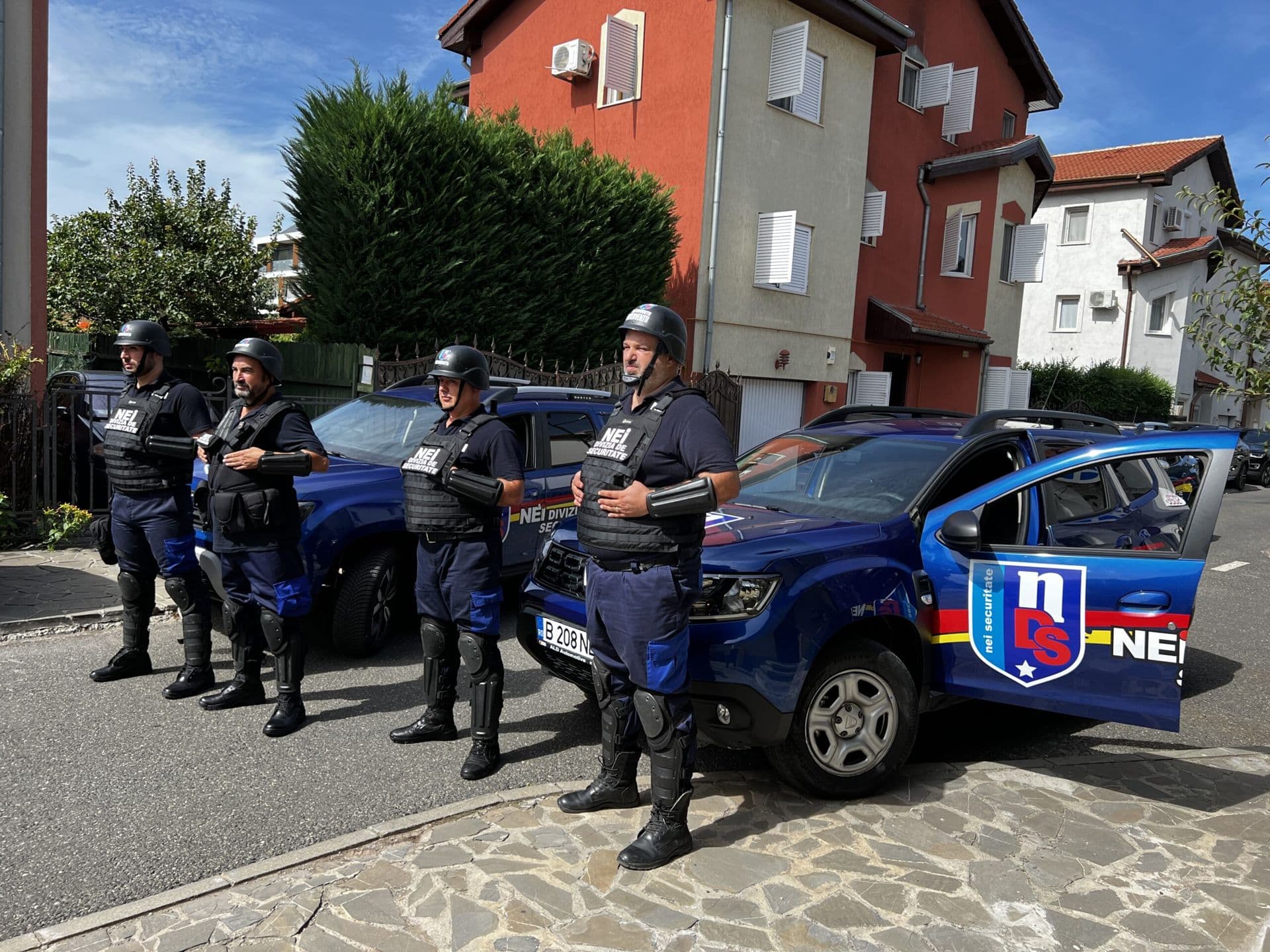 Echipaj NEI în echipament de protecție, lângă autovehiculele de intervenție