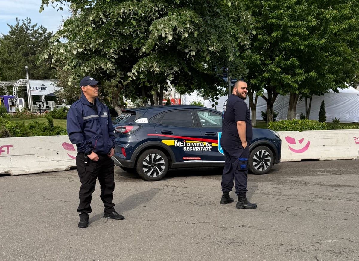 Doi agenți de pază NEI la un eveniment, lângă autovehiculul companiei